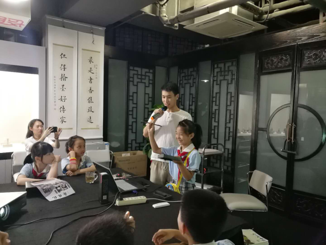 小朋友在志愿者老师指导下体验抄手砚的用法.