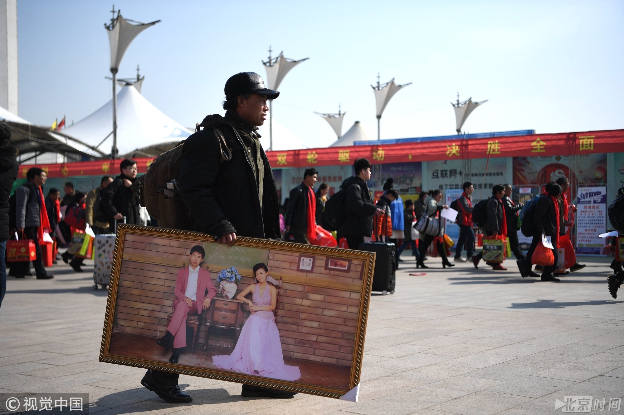 2018年2月7日，在安徽阜阳市站前广场，从北京打工回来的张银文带着儿子的婚纱照回家，他告诉记者，这是儿子之前放在北京家里的婚纱照，因为儿子现在去武汉打工不回北京这次就给带回来了。韩苏原/摄