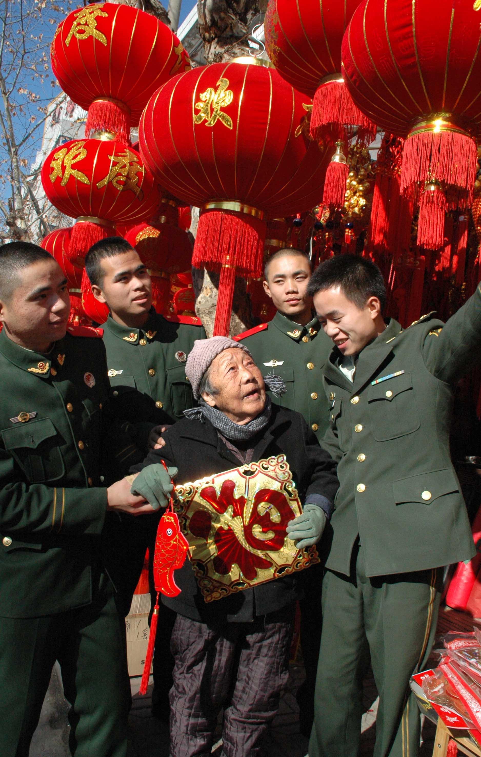 2014年1月25日,武警浙江总队温岭县中队官兵搀扶着帮扶对象林奶奶挑选福字、中国结等年货饰品。