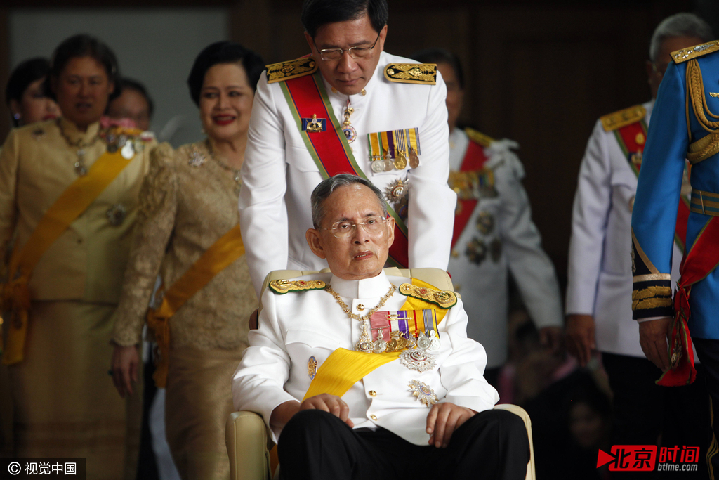 2011年12月5日，泰国曼谷，泰王普密蓬-阿杜德（中）坐在轮椅上，他离开诗里叻医院去往皇宫参加国王的生日庆典。自2009年9月因多种疾病住院治疗之后，泰国国王就一直长期居住在医院，很少露面。