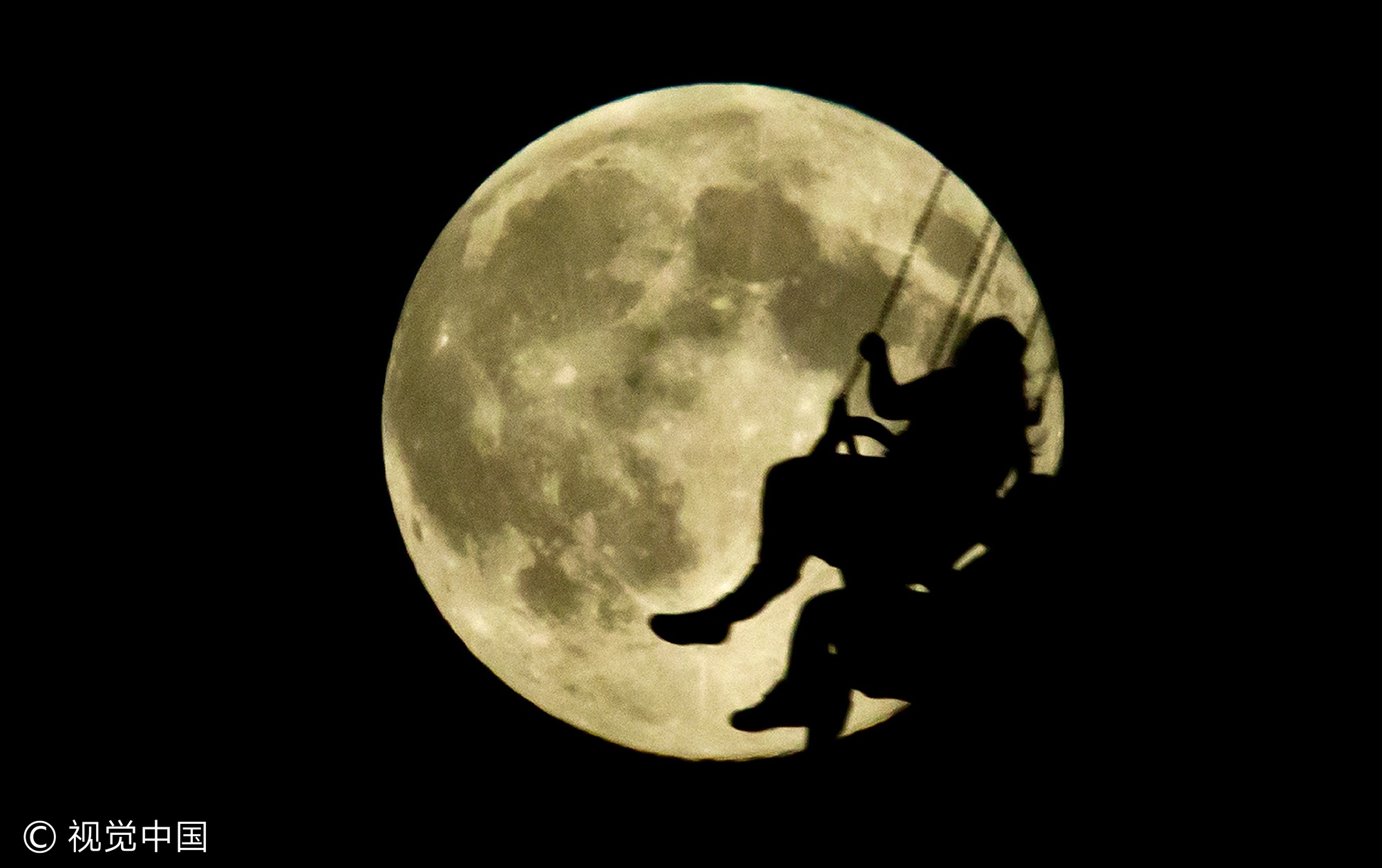 当地时间2013年8月20日,加拿大温哥华,参加太平洋国家展览会游乐会的游人剪影映在月亮上。