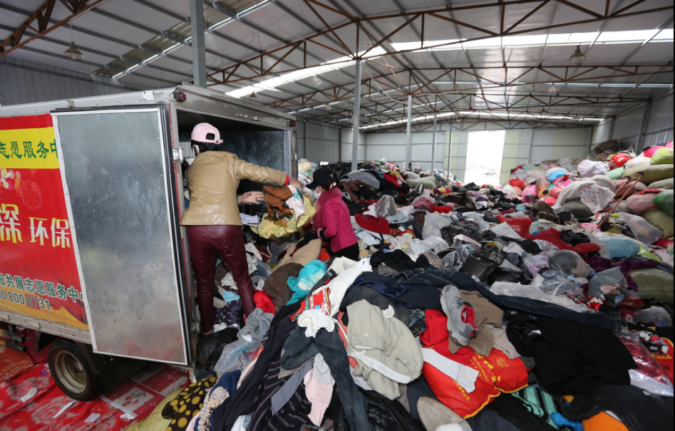 2016年10月13日，湖北省襄阳市，旧衣分拣中心里面堆放的旧衣物堆成了小山，又有一车衣服从“旧衣回收箱”拉到此处进行分拣。