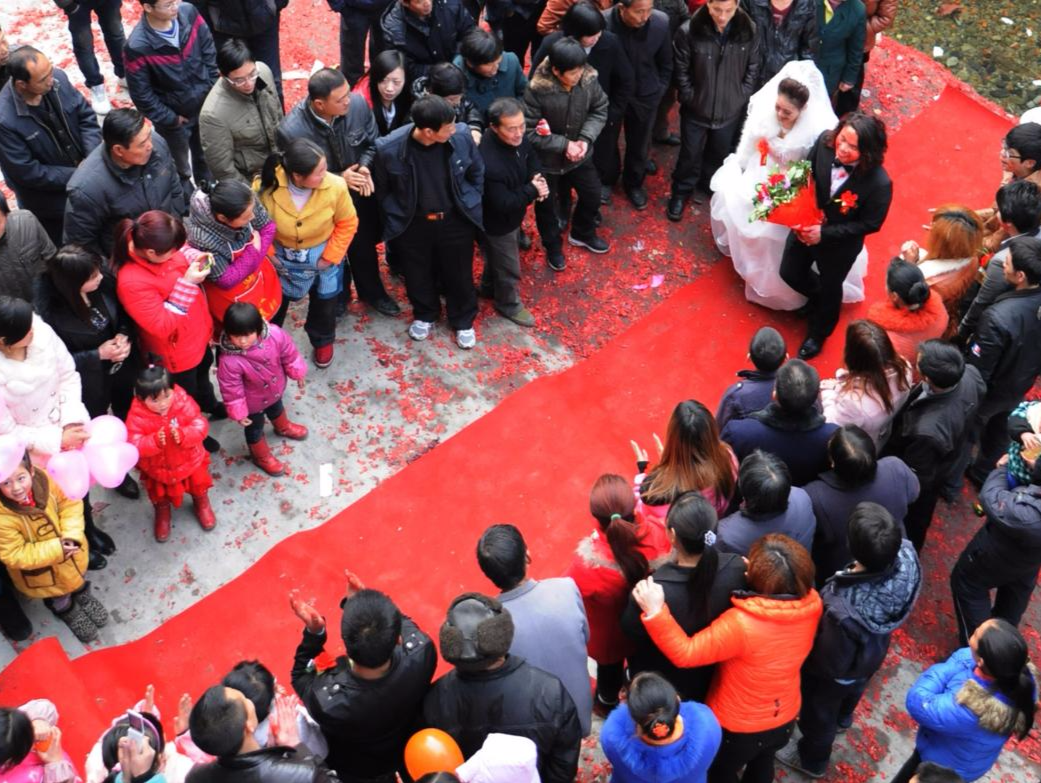 2012年，陕西安康一个小镇上，一对新人走在红地毯上，现在农村婚礼也追求时髦和潮流，因为人们的生活水平都提高了。现在一些地区的彩礼也是伤不起，彩礼几万到几十万不等，为了结婚背上债务的大有人在。图片来源：姚忠智/视觉中国
