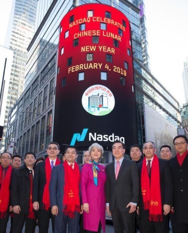当地时间2月4日，为迎接中国农历猪年春节，中国驻纽约总领事黄屏在纳斯达克纽约时代广场总部，为当天股市开市敲钟。中资机构代表，纳斯达克高管等40余人出席仪式。图为纳斯达克位于时代广场的户外大屏幕显示敲钟仪式内容，黄屏与中资机构代表等在屏幕下合影。