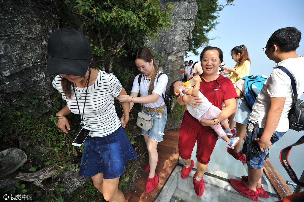 游客们在盘龙崖玻璃栈道上游玩拍照。