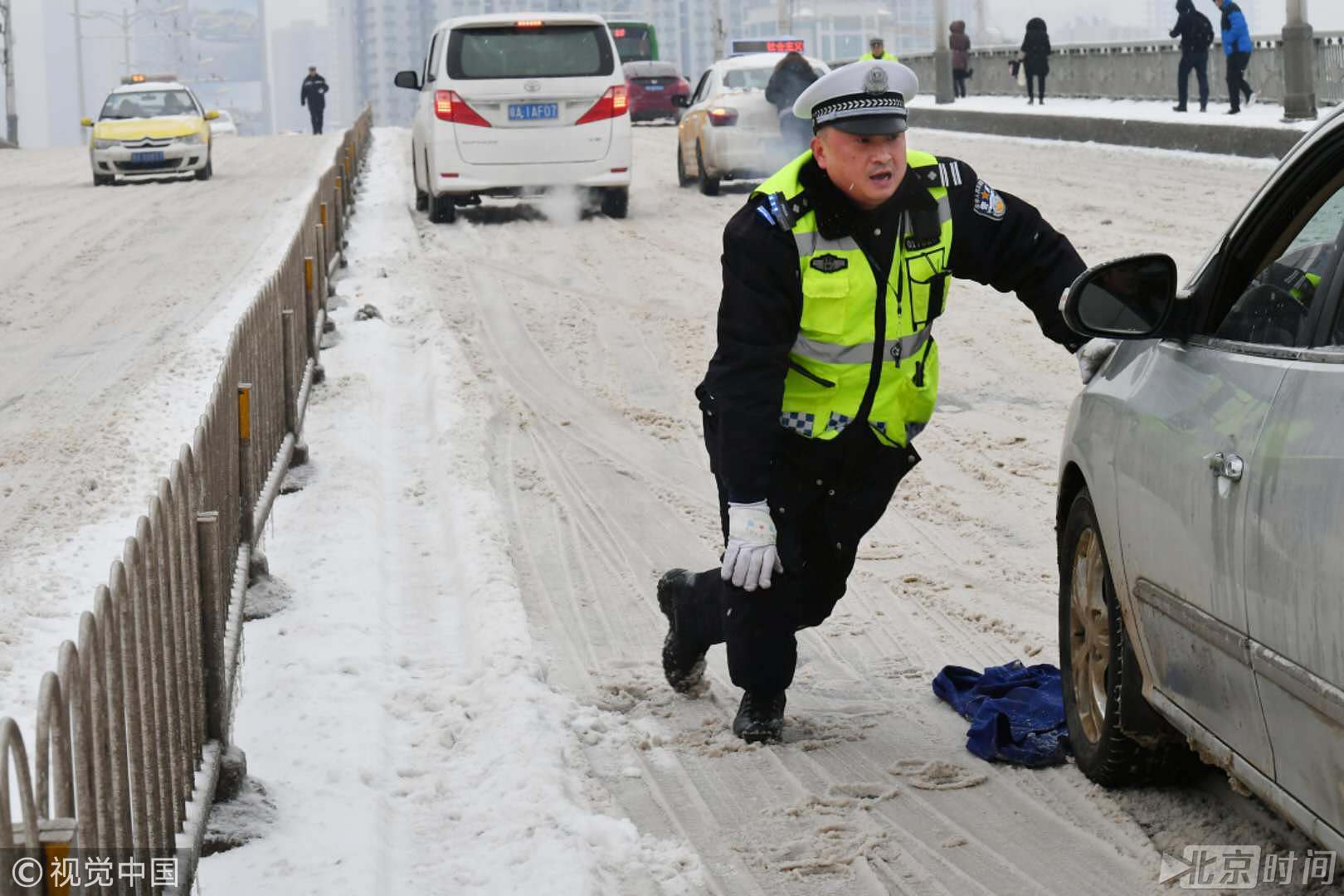 风雪中上演感动瞬间 武汉交警脱下上衣放冰面上推车