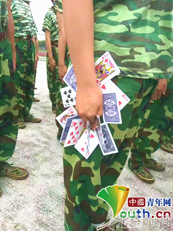 军训的教官们为了达到完美的训练效果,其训练手段可谓是“花样百出”。江西外贸外语职业学院的军训教官为了让新生的站姿更加挺拔,防止学生训练时偷懒,竟想出让新生“手夹10余张扑克牌”的花招。照片在网上发布后,有网友调侃说:“坐下就可以斗地主了。”(来源:中国青年网)