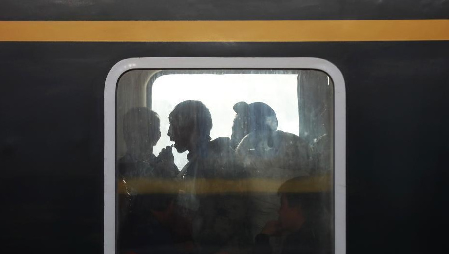 1月24日，透过停靠在南京火车站的列车车窗，车内的乘客或站、或坐、或沉思。随着春节的临近，越来越多的民众带上行李，踏上旅途。