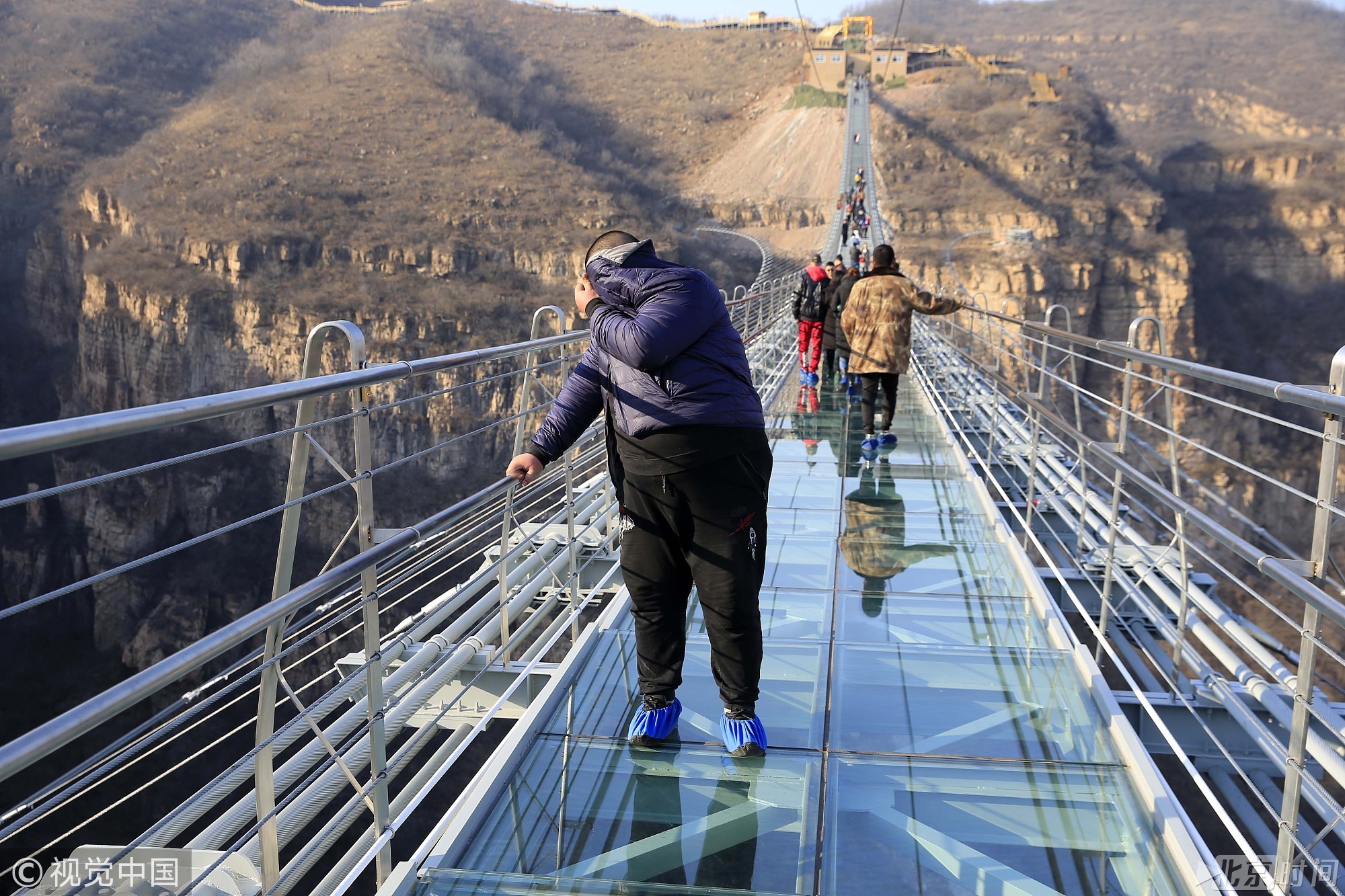 图为2017年12月26日，游客在红崖谷景区玻璃桥上行走体验。