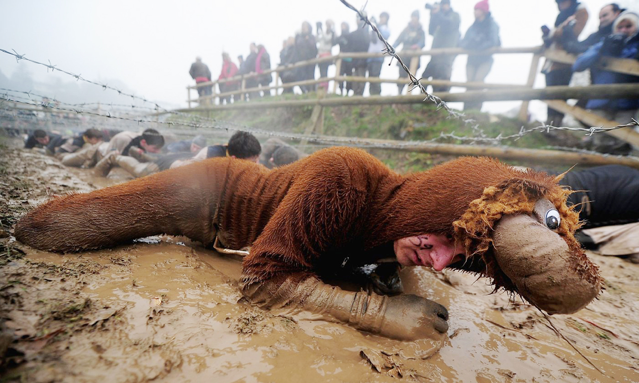 你会发现一些障碍，包括“疯狂猴子爬”——抹着泥和黄油在一个接近零度的泥水坑里穿行。图为选手穿越铁丝网。