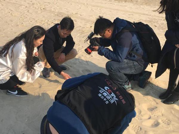 图为主持人蒋炎诺和蓝色金田董事长向中帅在沙滩的拍摄现场