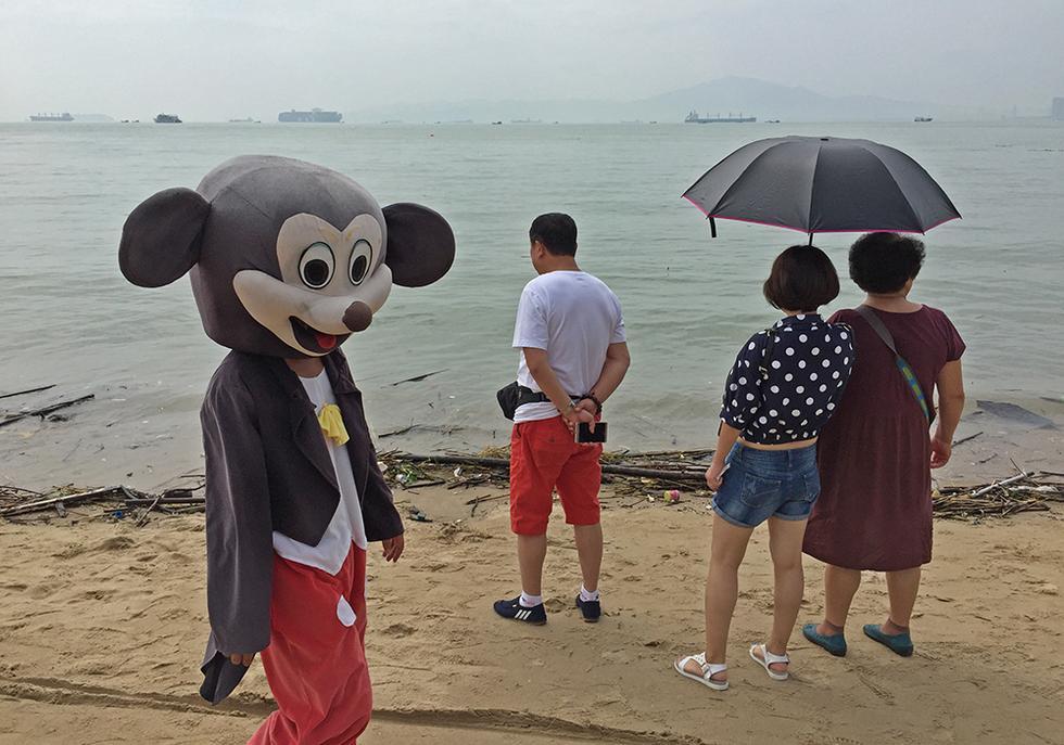 图为10月1日上午,厦门白城海滩,由于游客少,这些扮成聋哑人穿上米奇人偶的骗子,生意也变差。