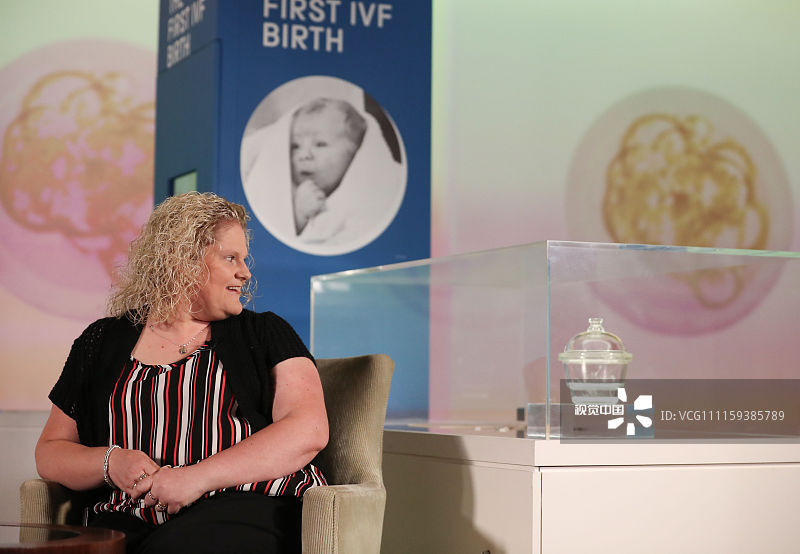 当地时间2018年7月23日，英国伦敦，世界首个试管婴儿路易丝·布朗出席科学博物馆展览，与她的胚胎使用过的玻璃干燥器合影，纪念世界上首个试管婴儿诞生40周年。1978年7月25日，世界上第一个试管婴儿路易丝·布朗在英国诞生，标志着人类在胚胎学上的重大进步。