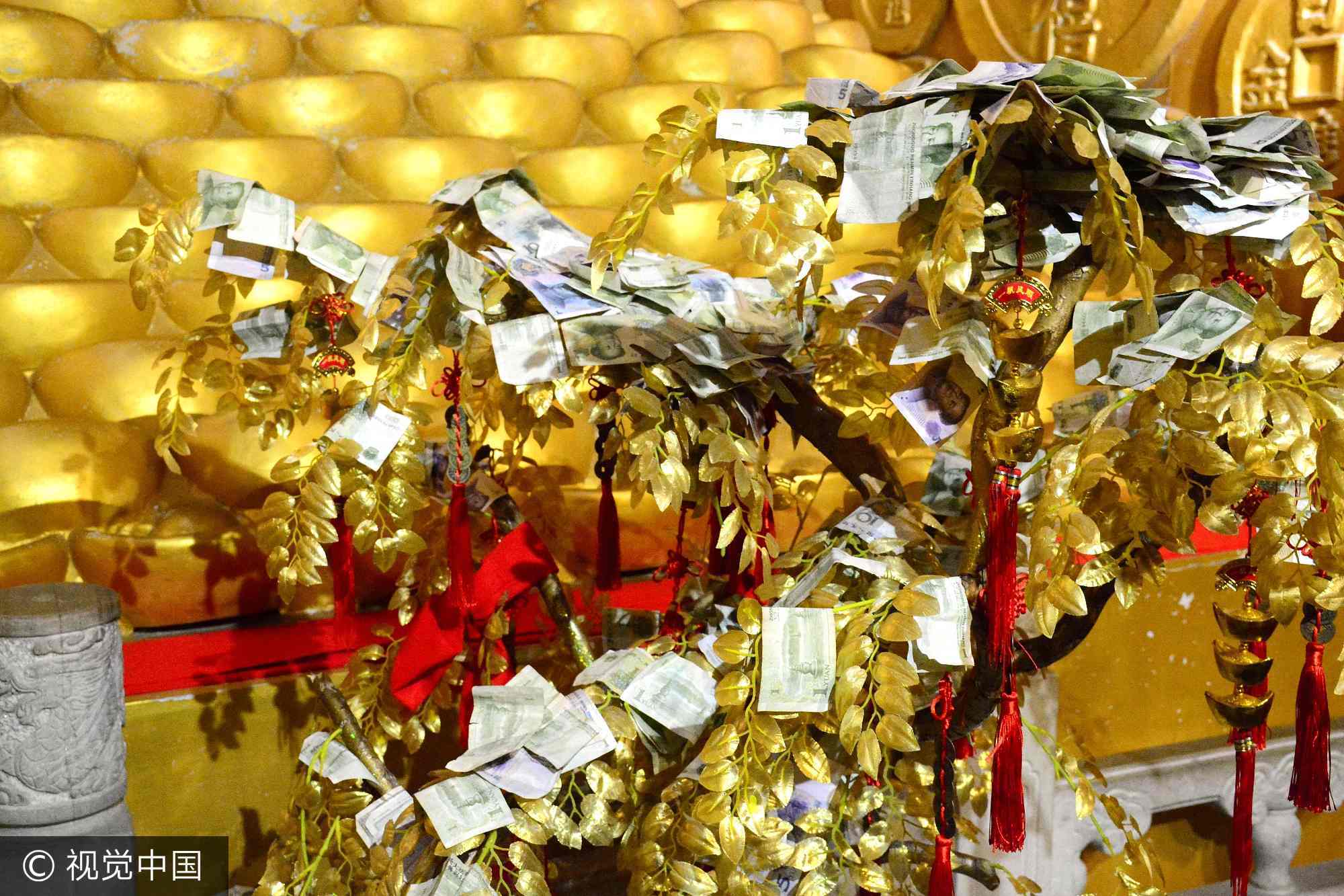 雕像前面摆有一组金色摇钱树，寓意财源广进生意兴隆。