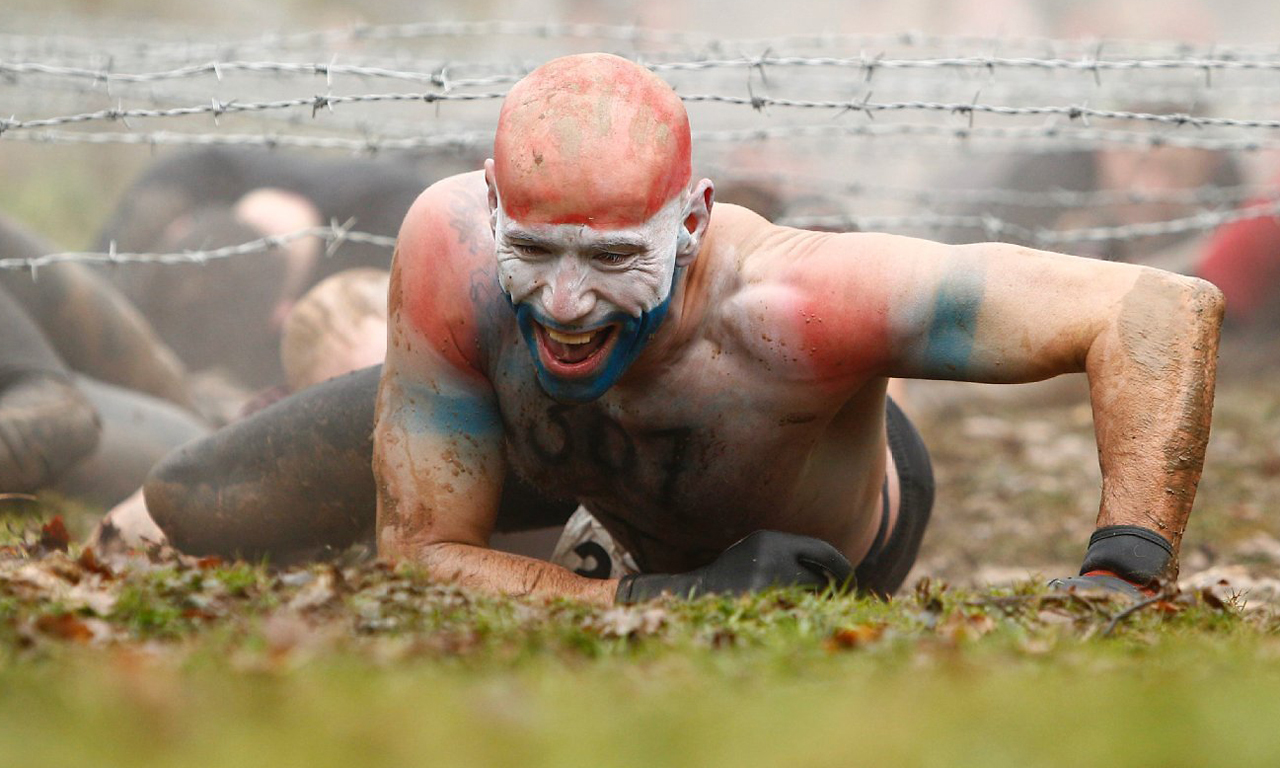 在比赛中，选手将会经历大约25项高难度障碍，这些障碍是由英国特种部队受到军事启发而设计的。图为选手穿越铁丝网。
