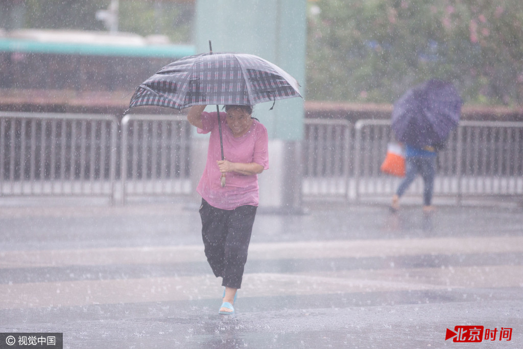图为冒雨前行的市民。