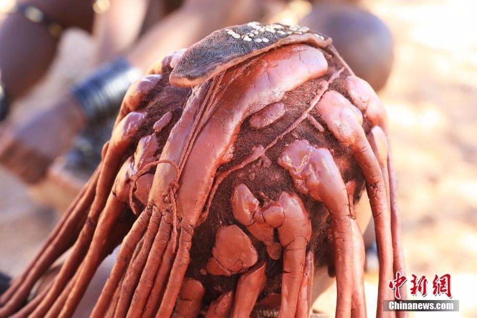 生活在纳米比亚的辛巴族又称“红泥族”，是非洲最后保持原始生态的部落之一。作为该部落最大特色，辛巴族女子终生不洗澡，且常年袒露上身，尤其喜欢把一种红色矿物粉末混合着奶油等涂抹在身上和头上。图为红泥族人头发。中新社记者 王曦 摄