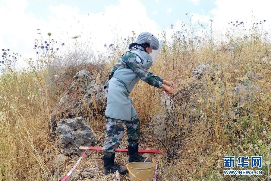 6月18日，在黎巴嫩南部与以色列临时边界“蓝线”附近一处雷场，女扫雷手杨怡鑫在割除雷场陡坡上的植被。