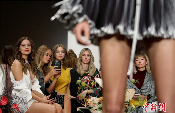 观众们在t台中央观摩模特走秀.