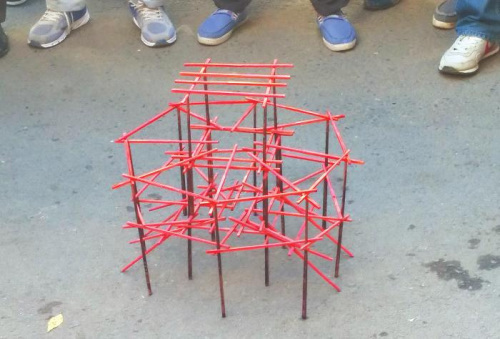 这名男子拿着一大把涂有红黑两种颜色的筷子,一根一根地搭建起来