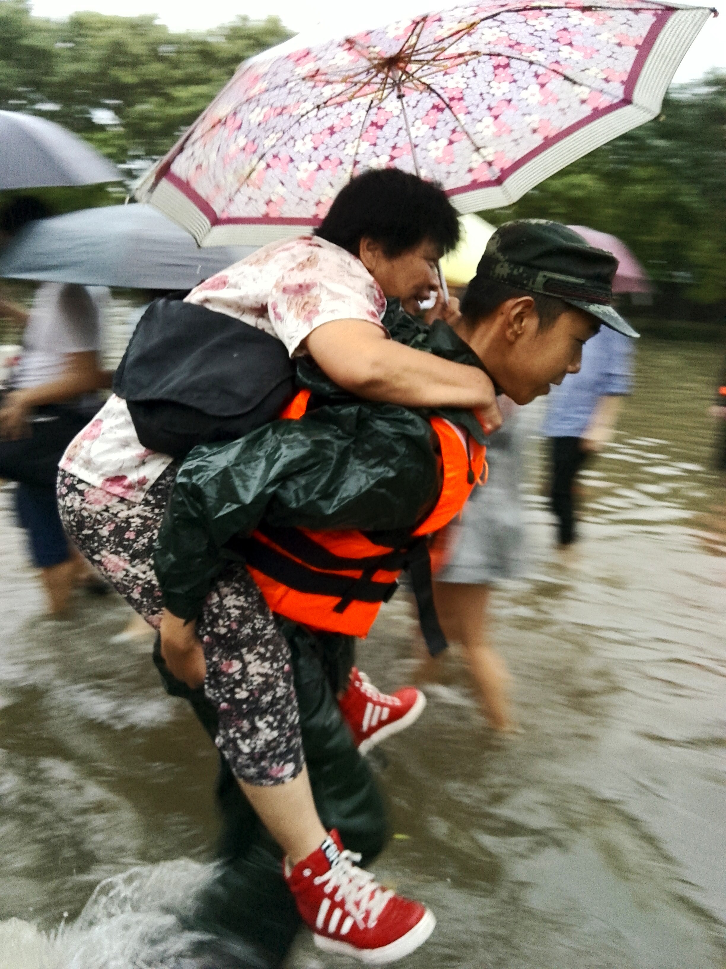 武警北京总队官兵帮助行动不便的行人通过复杂水路段。焦一鸣摄