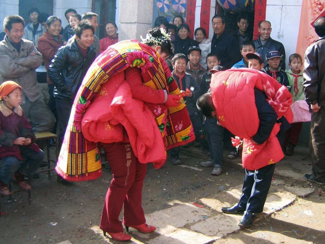 2006年，印台区后齐村，按照习俗新郎新娘身上绑着红色的被子互拜。图片来源：姚忠智/视觉中国