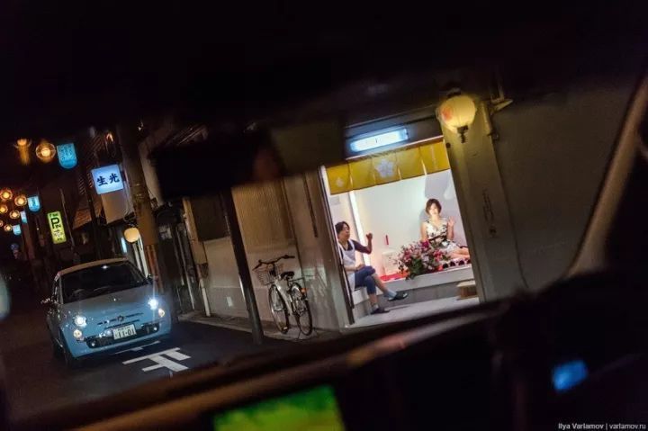 照片中应该不难看出飞田新地的日常模样:每个小白牌子上写着店铺的名字，每家店铺都是一个很小的房间，大门对外敞开。