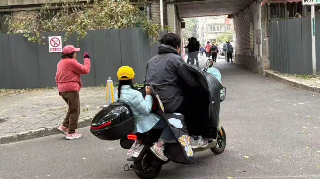 真危险！电动自行车后座，孩子不戴头盔，还看视频、吃烤肠……