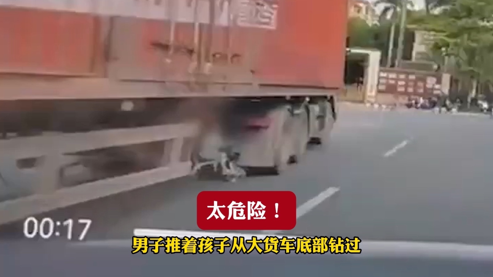 太危险！男子推着孩子从大货车底部钻过